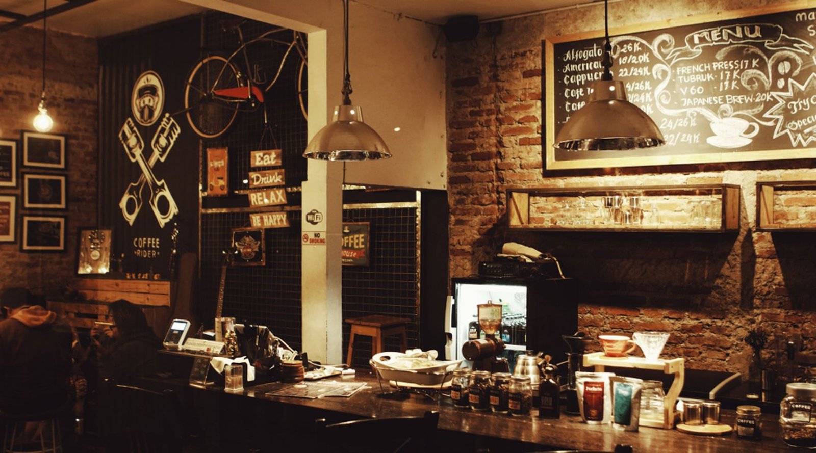 Warm, low lit bistro dining room with brick walls and hanging lamps