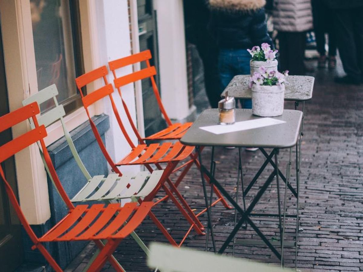 Outdoor patio seating with small tables and chairs under greenery